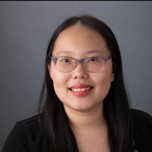 A headshot of FeiFei Le Pic smiling with a gray background.