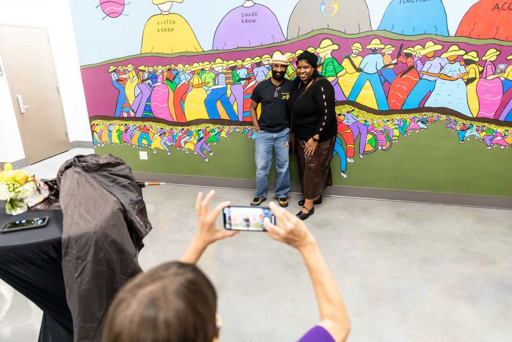 Artist and student at the ACC TRHT center in front of a newly completed mural
